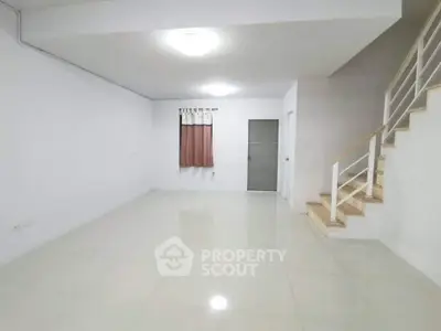 Spacious and bright interior with modern staircase and tiled flooring, perfect for customization.