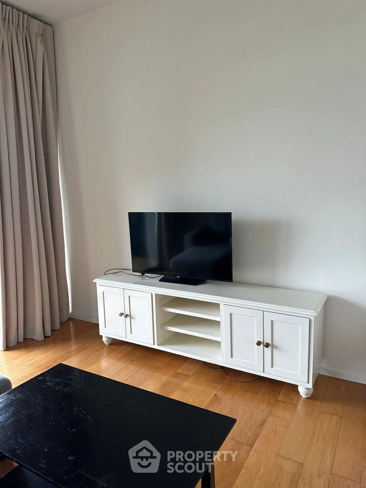 Modern living room with sleek TV setup and elegant wooden flooring.