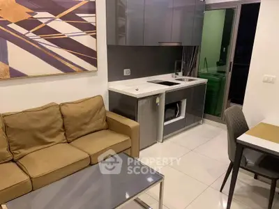 Modern compact kitchen with sleek cabinetry and cozy living area in stylish apartment.