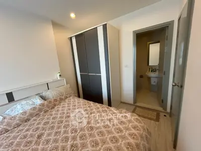 Cozy bedroom with ensuite bathroom and modern wardrobe in stylish apartment.