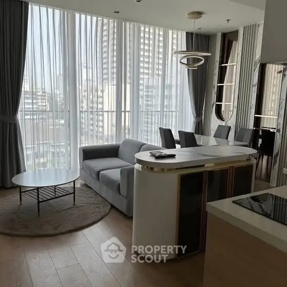 Modern living room with elegant dining area and city view, featuring sleek furniture and floor-to-ceiling windows.