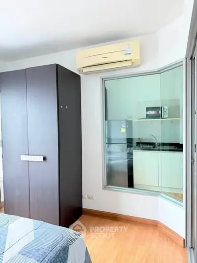 Modern bedroom with wardrobe and view into compact kitchen area