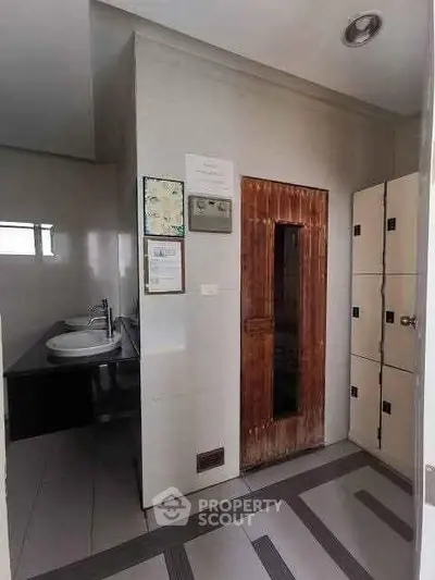 Modern bathroom with dual sinks and wooden sauna door in sleek real estate property.