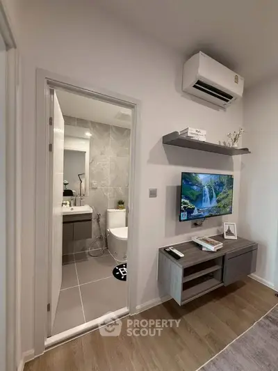 Modern living room with wall-mounted TV and view into stylish bathroom