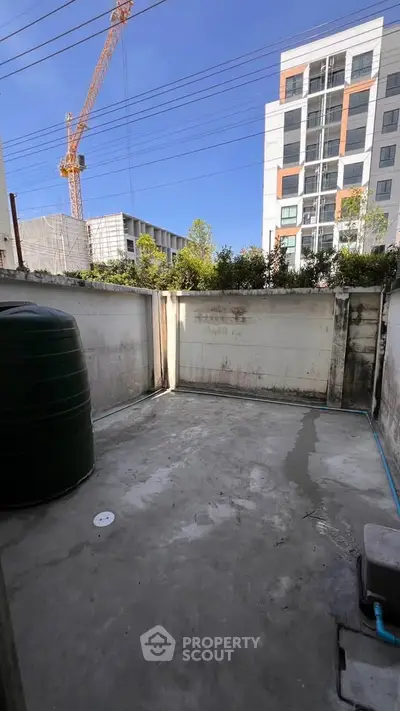 Spacious outdoor area with potential for garden or patio, featuring urban views and construction crane in background.