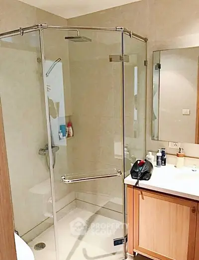 Modern bathroom with glass shower enclosure and wooden vanity in a stylish apartment.
