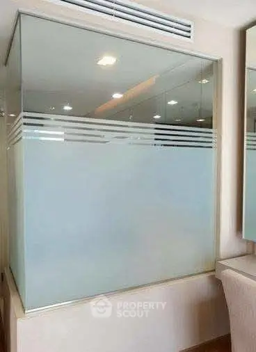 Modern bathroom with frosted glass partition and elegant lighting