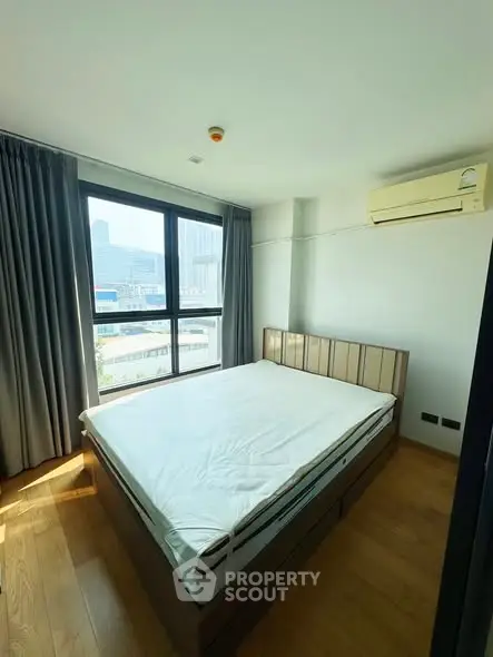 Bright bedroom with large window and city view, featuring a comfortable bed and air conditioning.