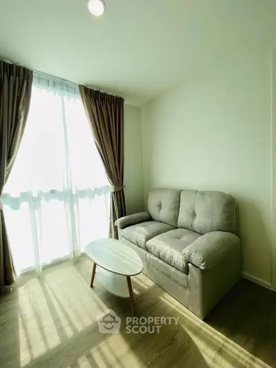 Bright living room with cozy sofa and natural light through large window.