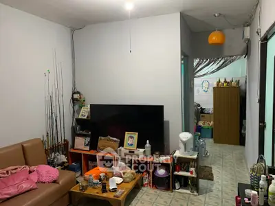 Cozy living room with TV, sofa, and fishing rods, ideal for relaxation.