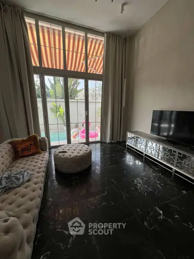 Luxurious living room with pool view, elegant furniture, and large windows for natural light.