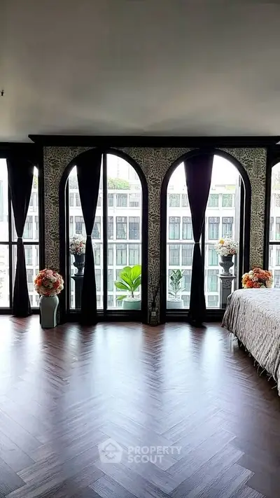 Luxurious bedroom with large windows offering stunning city view and elegant decor.