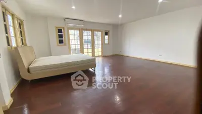 Spacious bedroom with wooden floors and large windows for natural light.