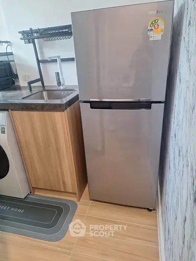 Modern kitchen with sleek fridge and washing machine in compact layout
