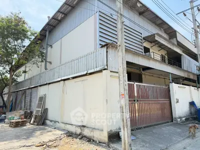 Industrial warehouse exterior with metal siding and gated entrance, ideal for storage or manufacturing.