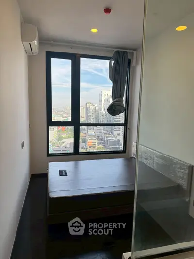 Modern bedroom with city view and large window, featuring sleek design and natural light.