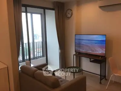 Modern living room with balcony view, featuring a cozy sofa and flat-screen TV, perfect for relaxation.
