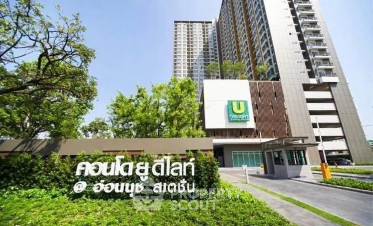 Modern high-rise condominium with lush greenery and sleek entrance in vibrant urban setting.