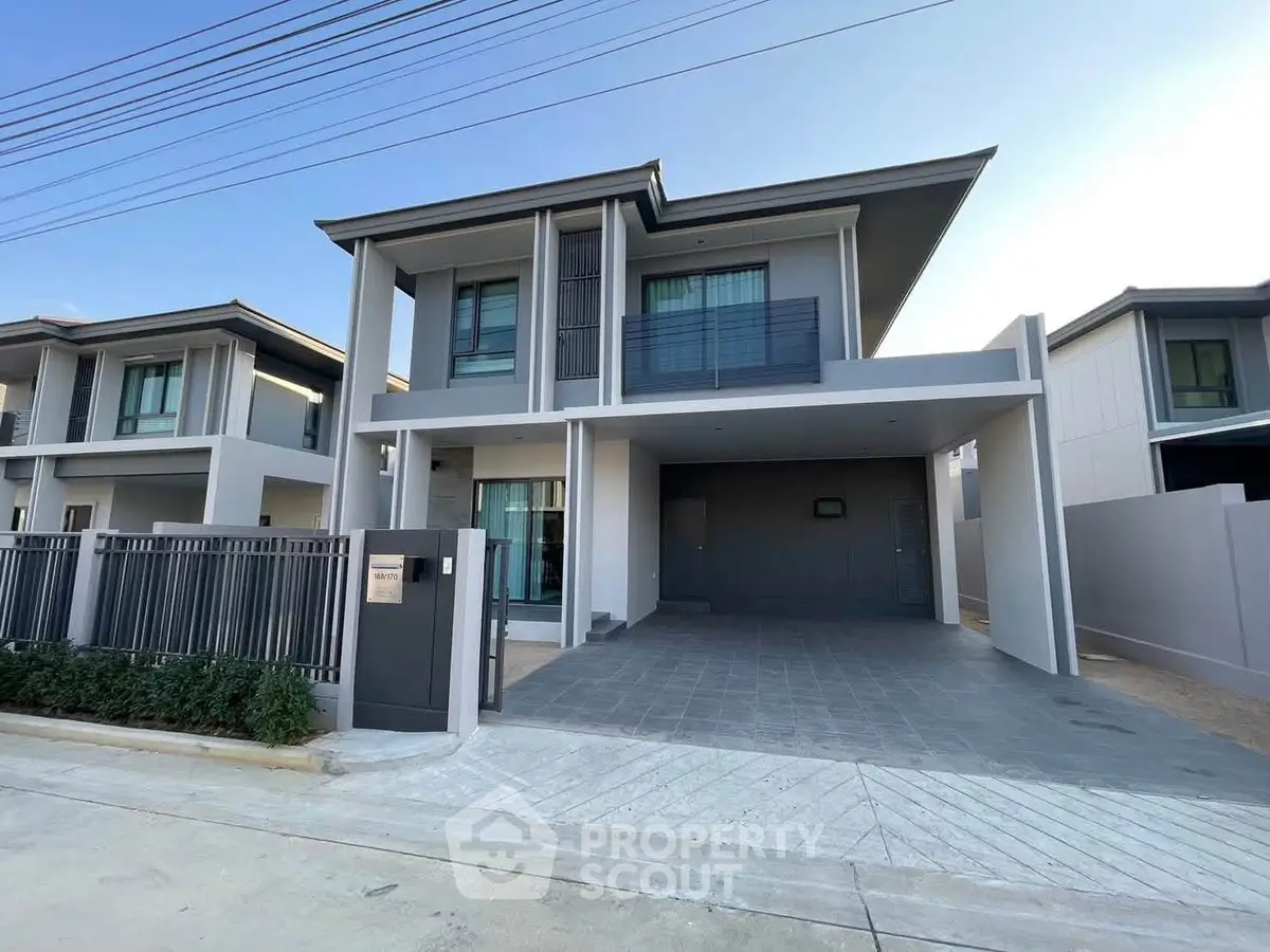Modern two-story house with sleek design and spacious driveway in a suburban neighborhood.