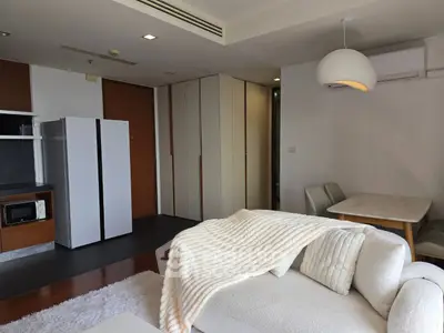 Modern living room with cozy white sofa, dining area, and sleek kitchen appliances in open layout.