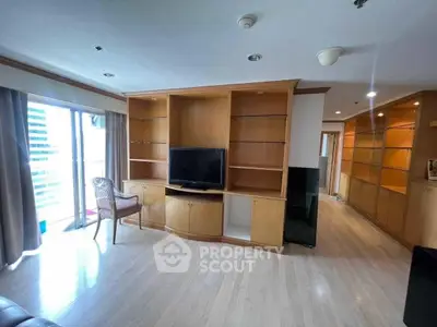 Spacious living room with built-in wooden shelves and large window view.