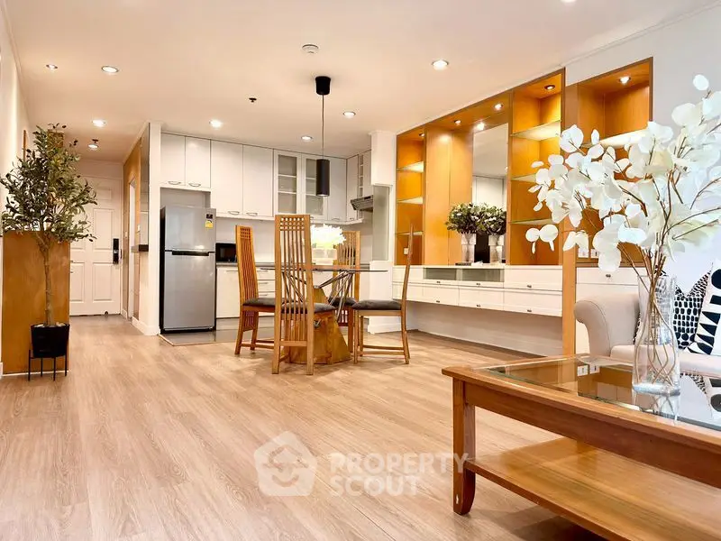 Spacious modern living room with open kitchen, elegant wooden flooring, and stylish decor.