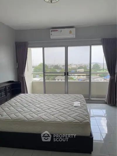 Spacious bedroom with large windows and city view, featuring a comfortable bed and modern decor.