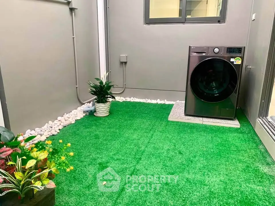 Charming outdoor laundry area with artificial grass and modern washing machine, perfect for urban living.