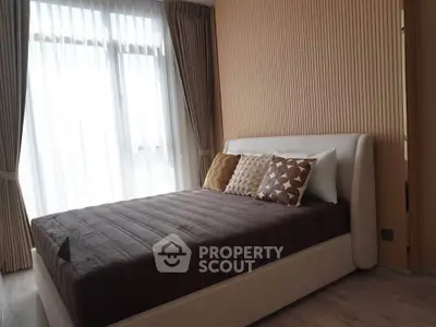 Elegant bedroom with cozy bed and stylish decor, featuring natural light from large windows.