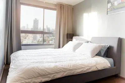 Bright and spacious bedroom with city view, featuring a large window and modern decor.