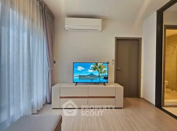 Modern living room with air conditioning and TV, featuring elegant curtains and a glimpse of a bathroom.