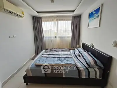 Spacious bedroom with modern decor and large window, featuring a comfortable bed and air conditioning.