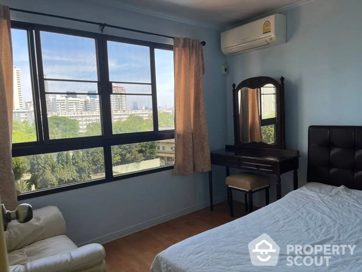 Spacious bedroom with large windows offering ample natural light and a serene city view, complemented by modern furnishings.