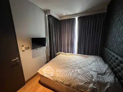 Cozy bedroom with modern decor and wall-mounted TV, featuring elegant curtains and soft lighting.