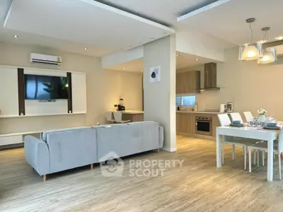 Spacious modern living room with open kitchen and dining area, featuring elegant decor and ample natural light.