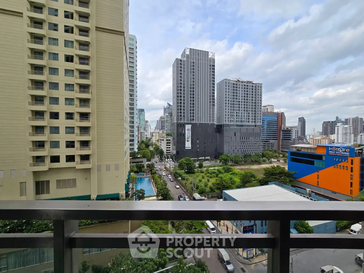 Stunning cityscape view from a high-rise balcony overlooking urban skyline and lush greenery.
