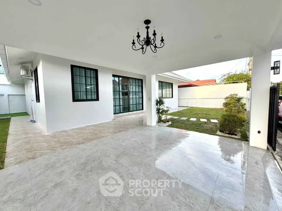 Spacious modern home exterior with elegant chandelier and lush garden view.