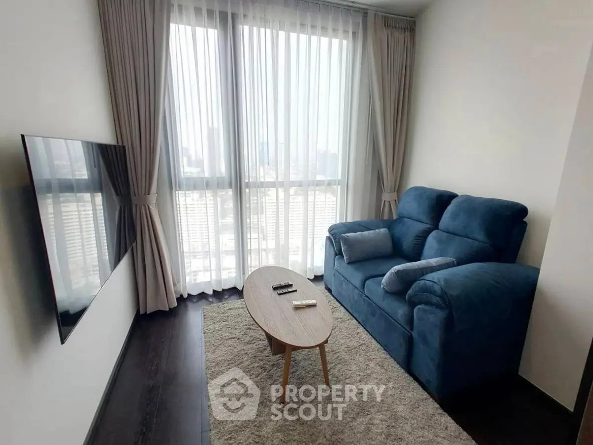 Cozy living room with plush blue sofa and city view through large windows.