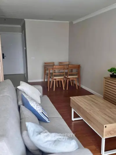 Modern living room with cozy sofa, wooden dining set, and stylish decor in a bright apartment.