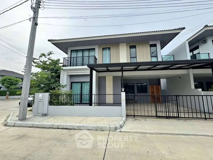 Modern two-story house with balcony and carport in suburban neighborhood.