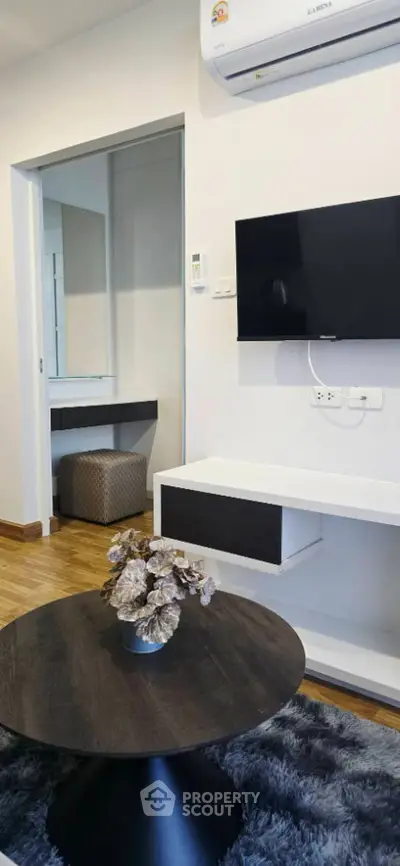 Modern living room with sleek TV setup and stylish decor in a cozy apartment.