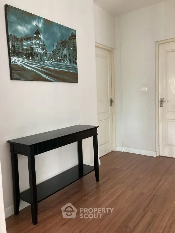 Minimalist hallway with wooden flooring and elegant black console table.
