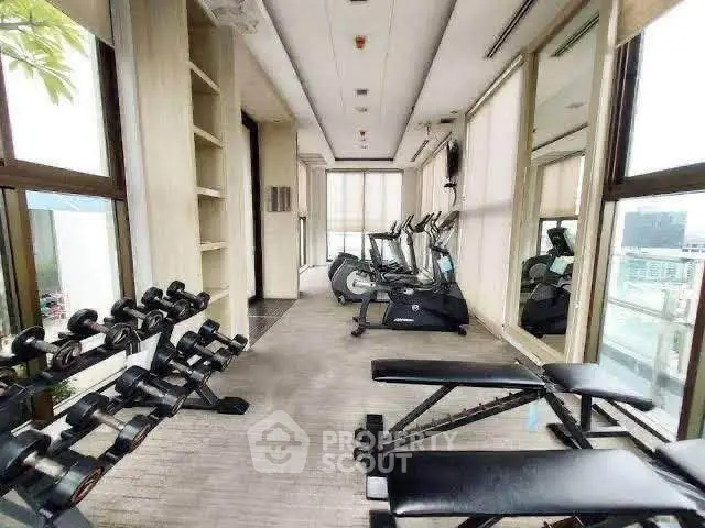 Modern gym with exercise equipment and city view, perfect for fitness enthusiasts.