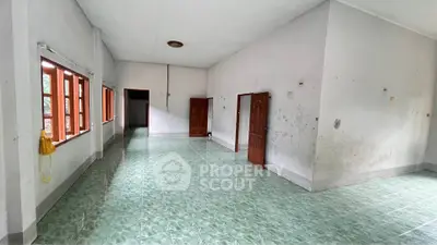 Spacious empty room with green tiled floor and wooden doors, ideal for customization.