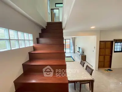 Spacious modern living area with wooden staircase and dining set