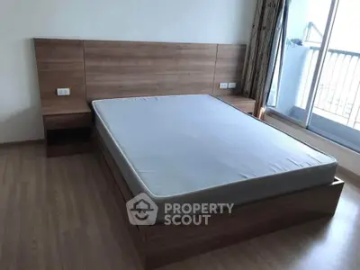 Spacious bedroom with modern wooden bed frame and balcony access, perfect for relaxation and comfort.