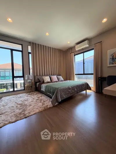 Spacious bedroom with large windows and modern decor, featuring a cozy bed and elegant lighting.