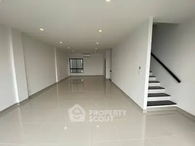 Spacious modern living room with sleek tile flooring and staircase