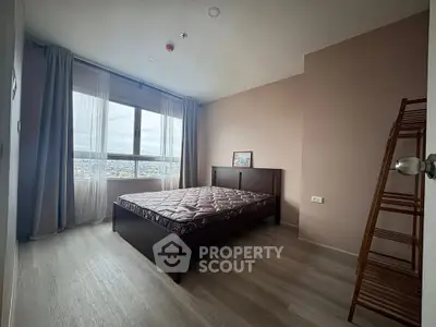 Spacious bedroom with large window offering stunning city views, featuring modern decor and ample natural light.