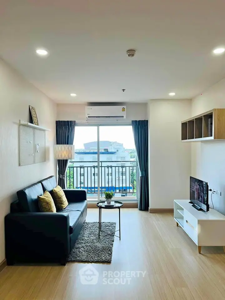 Modern living room with balcony view, stylish furniture, and natural light.